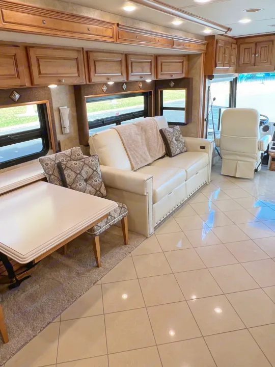 Spacious RV rental interior: cream sofa, dining table, wood cabinetry, and tiled floor, offering luxury comfort.. Itasca Meridian 2014