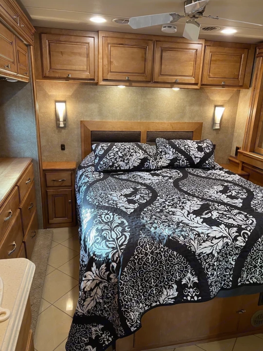 Comfortable RV rental bedroom with stylish black/white bedding, wood cabinets, and a ceiling fan. Great road trip lodging.. Itasca Meridian 2014