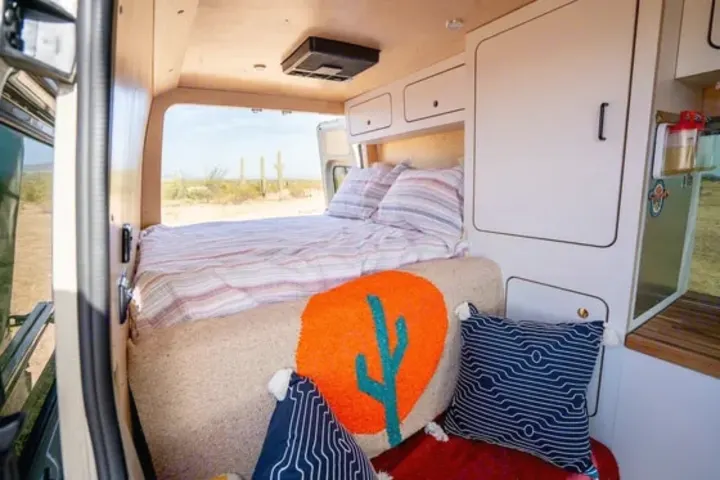 Cozy RV rental interior featuring a comfy bed, smart storage, and stunning desert views with saguaro cacti.. VanCraft VanCraft Class B 2022