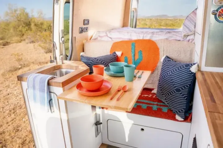Cozy rv rental interior with a compact kitchen and dining area, ready for adventure in the desert landscape.. VanCraft VanCraft Class B 2022