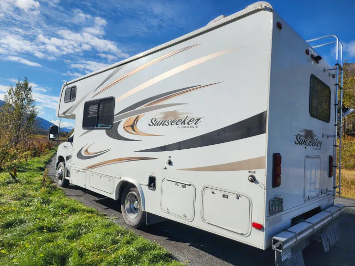 White Sunseeker RV rental parked on a scenic path under a blue sky, perfect for outdoor adventures.. Forest River Sunseeker 2014