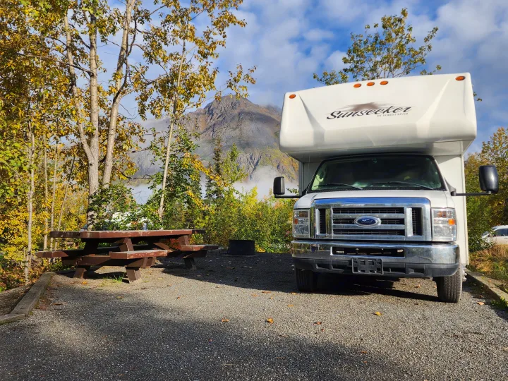 Experience nature with an RV rental: a white camper parked at a scenic autumn campsite with a picnic table & misty mountains.. Forest River Sunseeker 2014