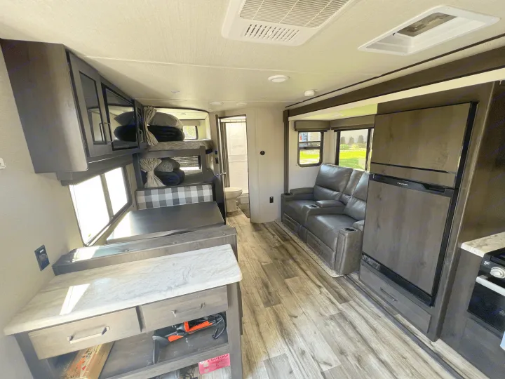Spacious RV rental interior featuring bunk beds, dinette, reclining sofa, and full kitchen amenities for comfortable travel.. Grand Design Transcend Xplor 2022