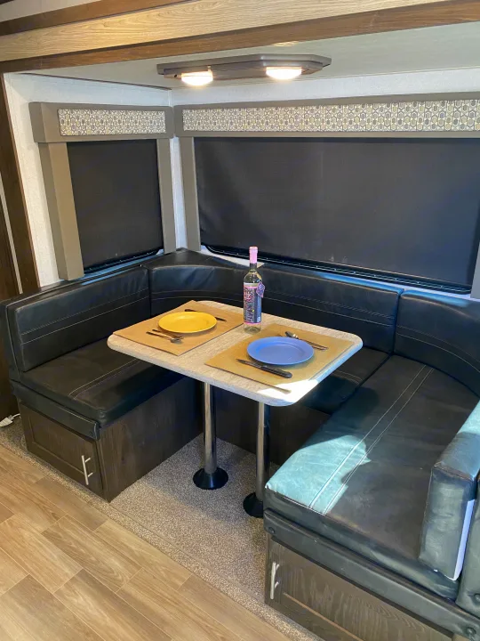 This RV rental features a modern dinette with U-shaped booth seating, a table set for two, and window blinds, offering a comfortable interior for travel.. Forest River Salem Hemisphere GLX 2019