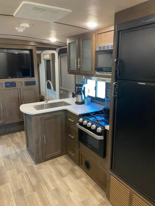 Spacious RV rental interior featuring a modern kitchen with island sink, stove, fridge, and TV. Ideal for travels.. Forest River Salem Hemisphere GLX 2019