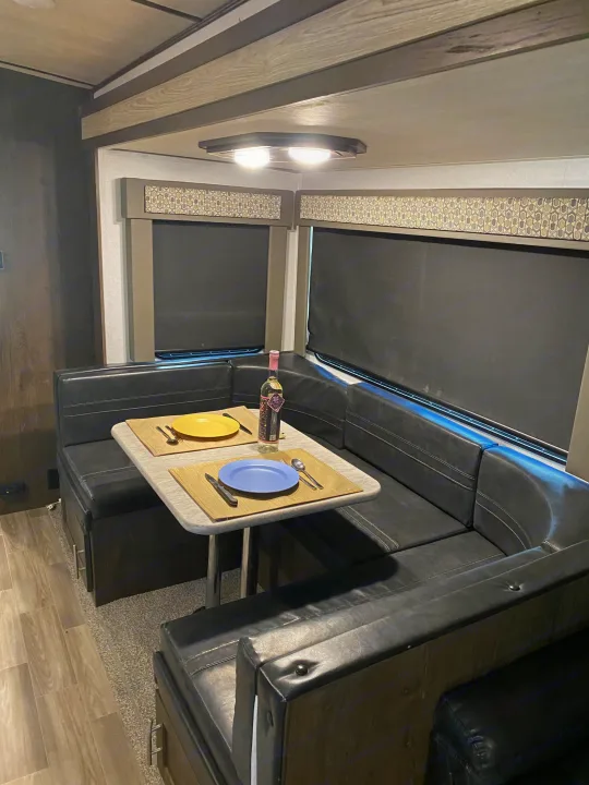 Cozy RV rental dinette: U-shaped seating, table set for two, and dark blinds covering windows for privacy.. Forest River Salem Hemisphere GLX 2019