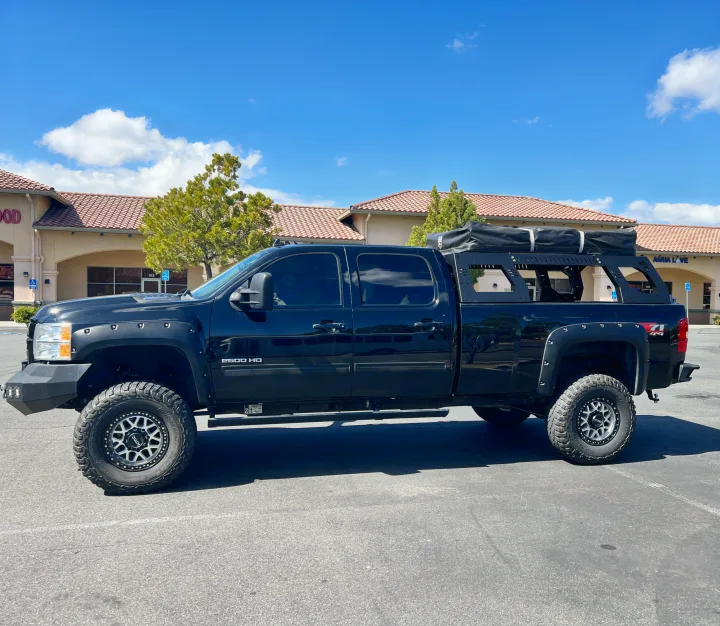 A black 2500 HD truck with a rooftop tent, resembling an RV rental for rugged outdoor adventures.. Chevrolet Silverado 2013