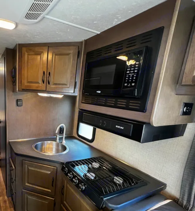 Spacious RV rental kitchen featuring a microwave, sink, and three-burner cooktop, perfect for road trip meals.. Thor Majestic 2019