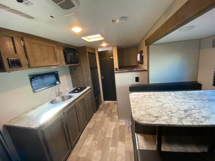 This RV rental interior features a functional kitchenette, dining area, and bunk beds, perfect for travel.. KZ Sportsman 2020