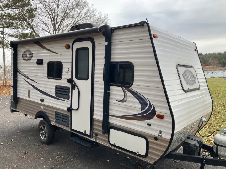 A pristine Viking travel trailer with a large awning and visible entry door, perfectly set up for an RV rental getaway.. Forest River Viking 2016