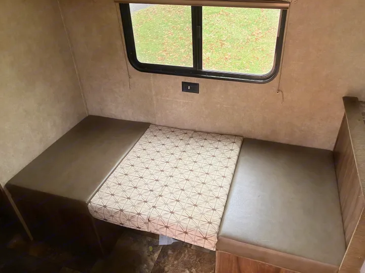 RV rental interior: Dinette featuring brown bench seats, a patterned cushion creating a bed, and a window with power outlet.. Forest River Viking 2016