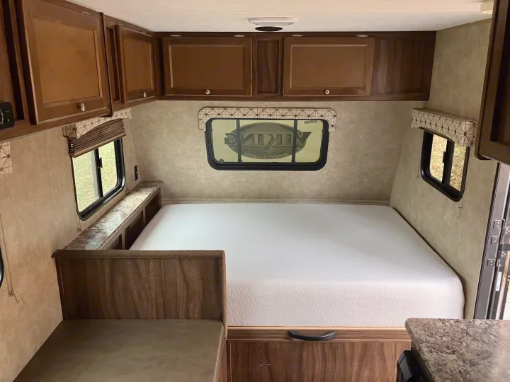Spacious RV rental interior featuring a comfortable bed, overhead storage cabinets, and multiple windows.. Forest River Viking 2016