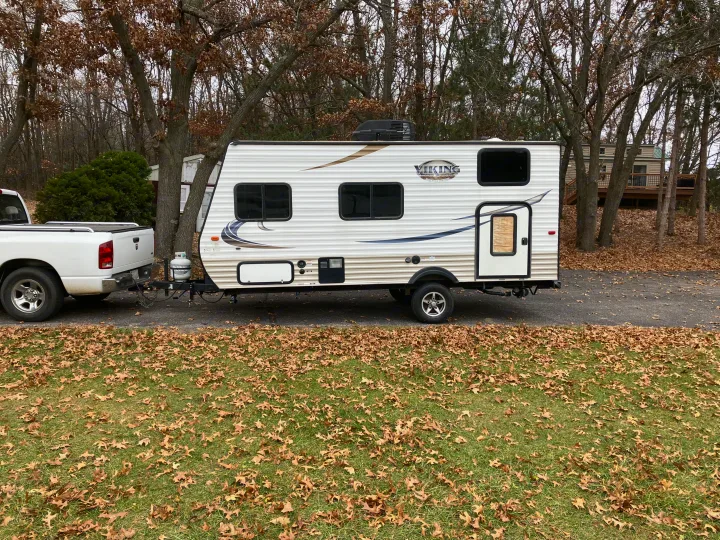 White pickup truck hitched to a Viking travel trailer, ready for your next rv rental adventure in a leafy outdoor setting.. Forest River Viking 2016