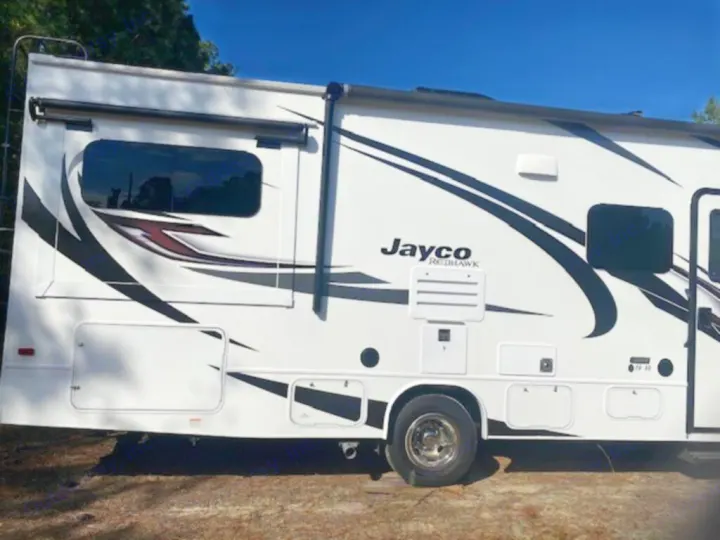 White Jayco Redhawk Class C RV rental, featuring stylish black and red graphics, parked outdoors. Perfect for your next trip.. Jayco Redhawk 2022