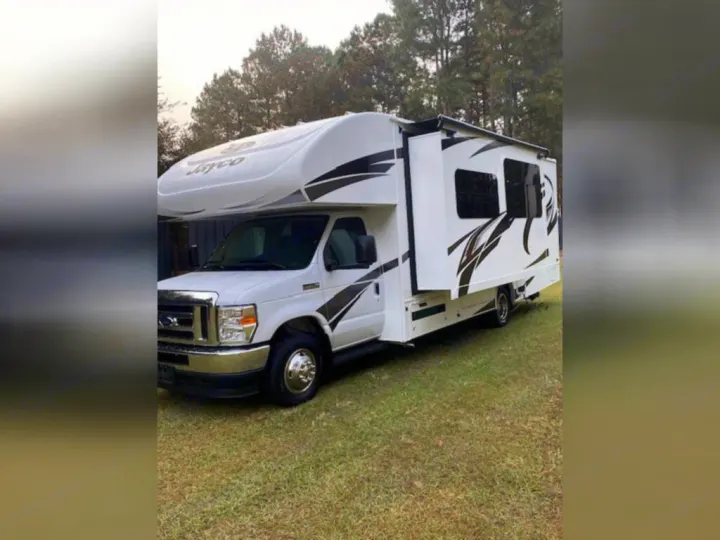White Jayco Class C RV rental parked on grass with an extended slide-out, perfect for your next camping adventure.. Jayco Redhawk 2022