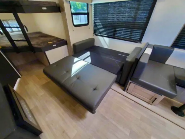 RV rental interior: Bunk beds, a gray convertible sofa bed, and light wood-look flooring. Bright space with windows.. KZ Connect C291BHK 2023
