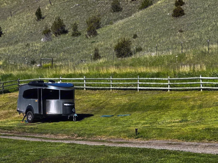 A sleek RV rental, similar to an Airstream Basecamp, nestled in a lush, fenced pasture by rolling hills.. Airstream Basecamp 2023