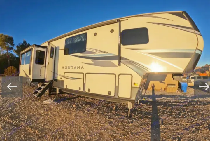 Montana fifth-wheel RV rental, cream-colored with graphics, parked outdoors with entry steps down.. Keystone RV Montana 2021