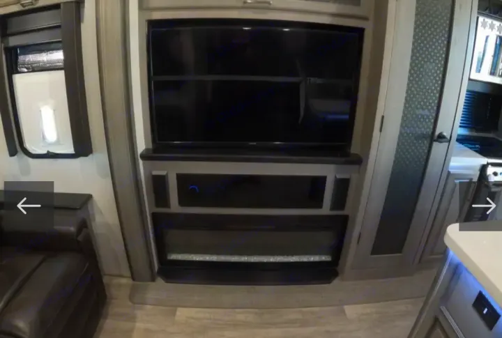 RV rental living space with a wall-mounted TV, built-in entertainment unit, and electric fireplace. Perfect for your travels.. Keystone RV Montana 2021