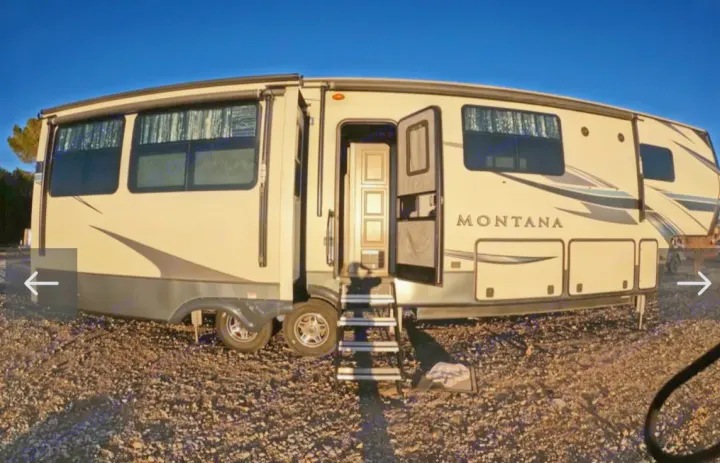 Explore this light-colored Montana fifth-wheel RV rental, featuring extended slides and an inviting open entry door on gravel.. Keystone RV Montana 2021