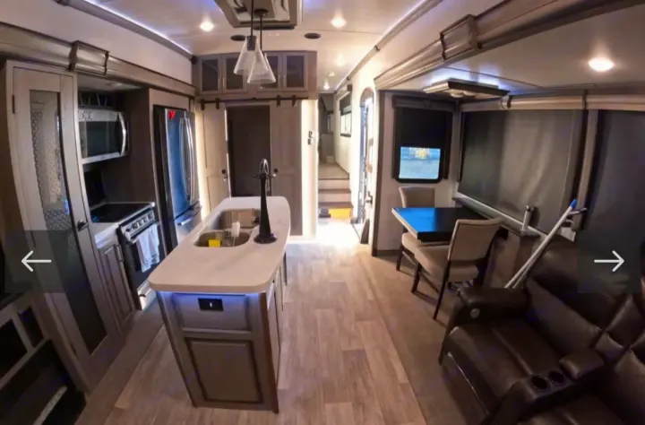 Spacious rv rental interior with modern kitchen island, dining table, and living area.. Keystone RV Montana 2021