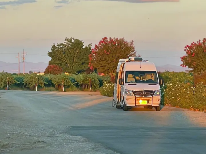 White rv rental van parked at a vineyard at sunset. Scenic travel for outdoor relaxation.. Airstream Interstate 2015