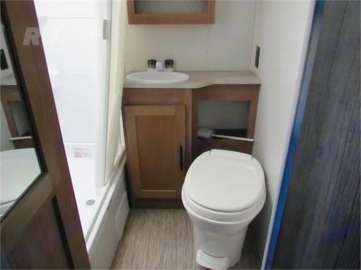 Compact RV rental bathroom features a sink, vanity, toilet, and shower/tub. Essential amenities for your travels.. Forest River No Boundaries 19.8 2021