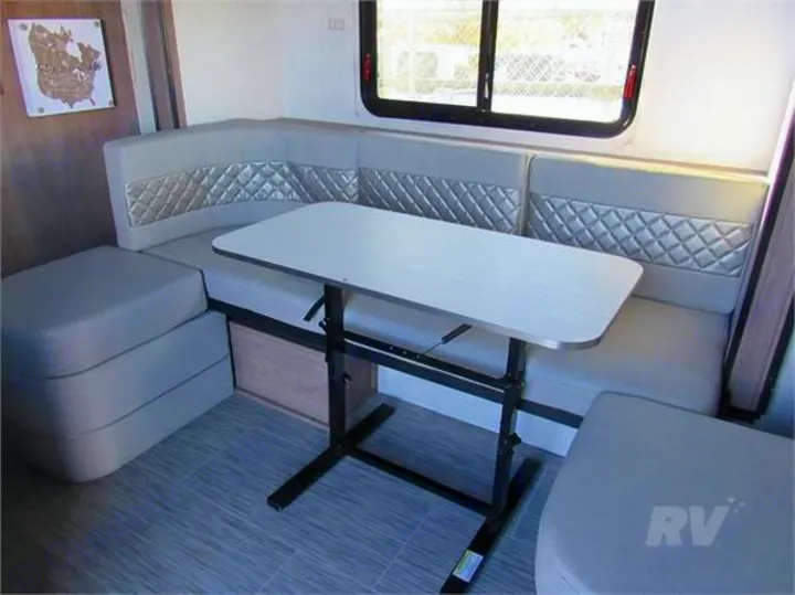 Spacious RV rental dinette with U-shaped seating, adjustable table, and light interior, perfect for meals and lounging.. Forest River No Boundaries 19.8 2021