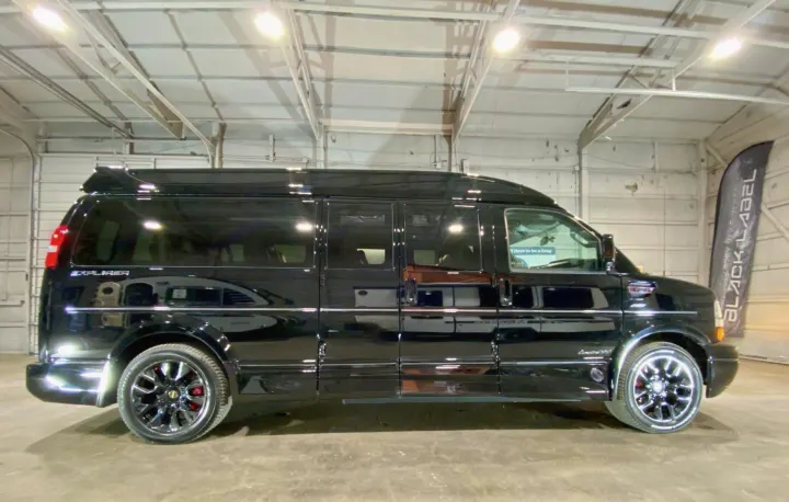 A polished black luxury conversion van, ideal for rv rental, is seen in a brightly lit garage. Great for comfortable travel.. Passenger Van 9 Passenger Van 2024