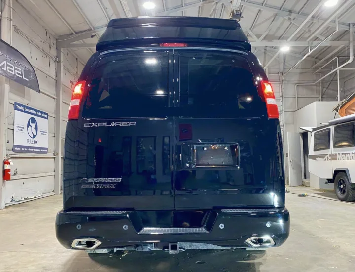 Rear view of a sleek black Explorer Express Max conversion van, ideal for rv rental or towing. High top and tow hitch visible.. Passenger Van 9 Passenger Van 2024