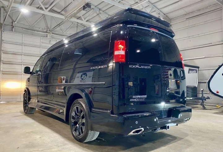 Rear view of a black Chevrolet Express Explorer conversion van with a raised roof, ideal for RV rental.. Passenger Van 9 Passenger Van 2024