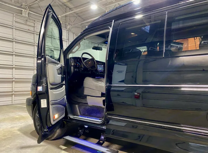 Ready for your next RV rental trip! Deluxe black van with open door, revealing plush interior and glowing retractable step.. Passenger Van 9 Passenger Van 2024