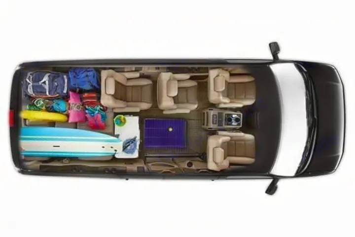 Overhead view: RV rental's spacious interior packed with passenger seats, a surfboard, pet crate, and travel gear.. Passenger Van 9 Passenger Van 2024