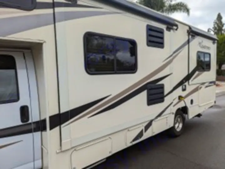This side view of a beige RV with graphic stripes shows its spacious design, perfect for an RV rental adventure.. Forest River Coachmen Freelander 2020