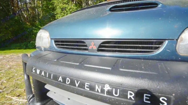 Close-up of a rugged Mitsubishi SUV, branded "Gwaii Adventures," perfect for exploring with an RV rental.. MITSUBISHI Delica 1997