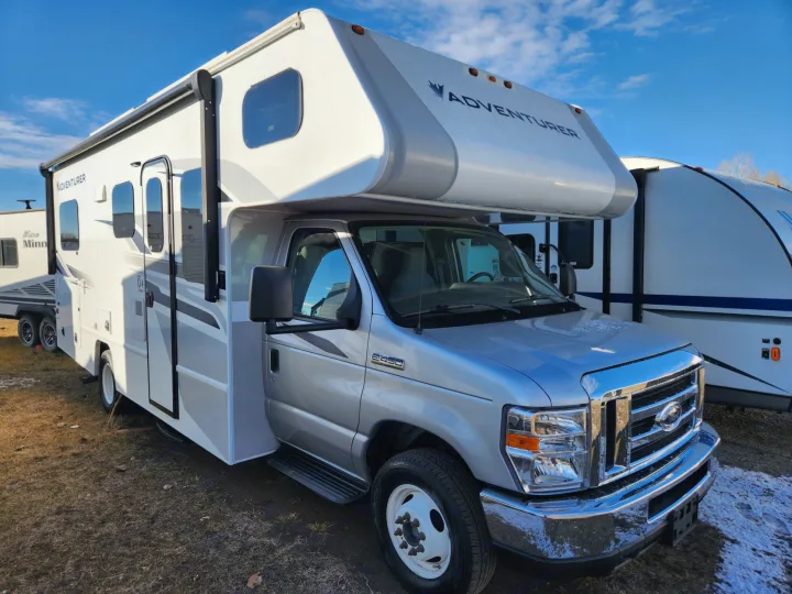 A silver Adventurer Class C motorhome, ideal for an rv rental adventure. Parked outdoors under a clear blue sky.. Adventurer 24DS 2020