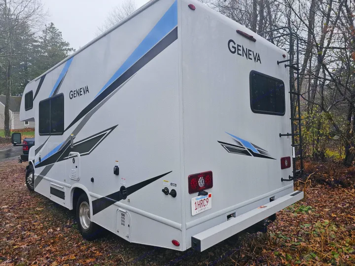 This white Geneva RV rental, a spacious motorhome with blue and black stripes, is parked on autumn leaves.. Other Other 2024