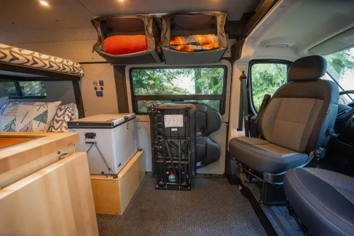 RV rental interior: cozy camper van setup with bunk bed, portable fridge, versatile seating, & overhead storage.. Ram ProMaster 2021