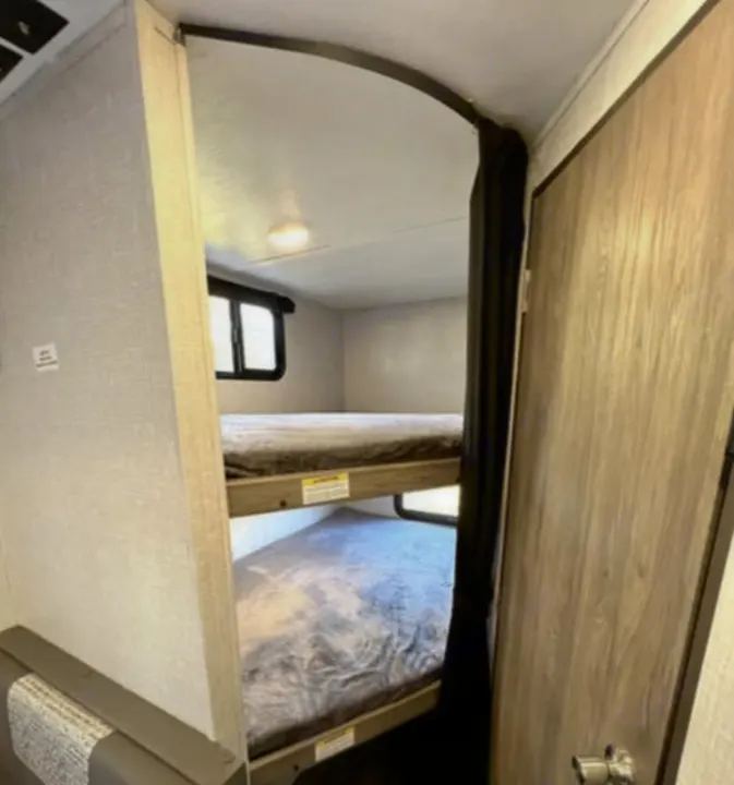 RV rental with cozy bunk beds inside. Features two beds, one above the other, offering comfortable sleeping for your trip.. Crossroads RV Zinger Lite 2022