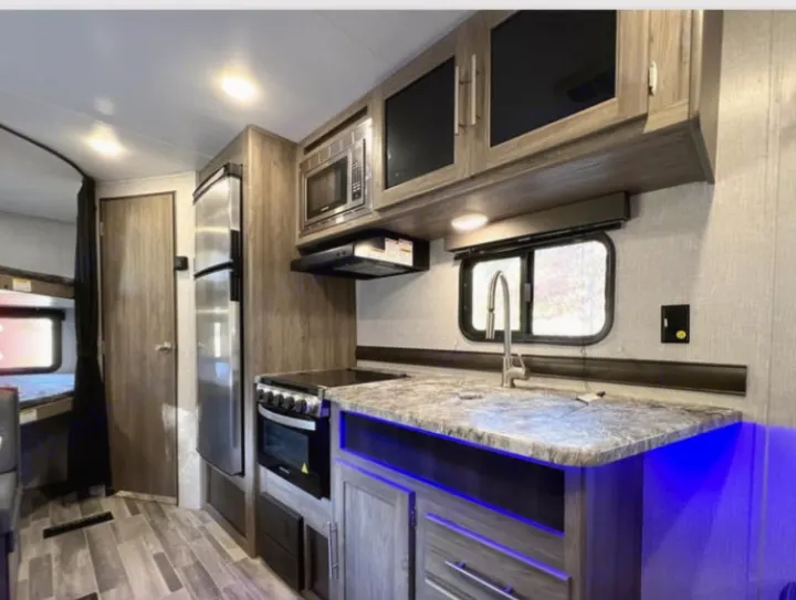 RV rental interior: a modern kitchen with a stove, sink, fridge, and nearby bunk beds for comfortable stays.. Crossroads RV Zinger Lite 2022