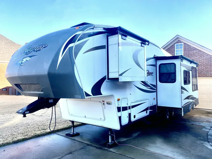 Large white and gray Cougar fifth-wheel RV rental, featuring extended slide-outs, parked outdoors.. Keystone Cougar 2012