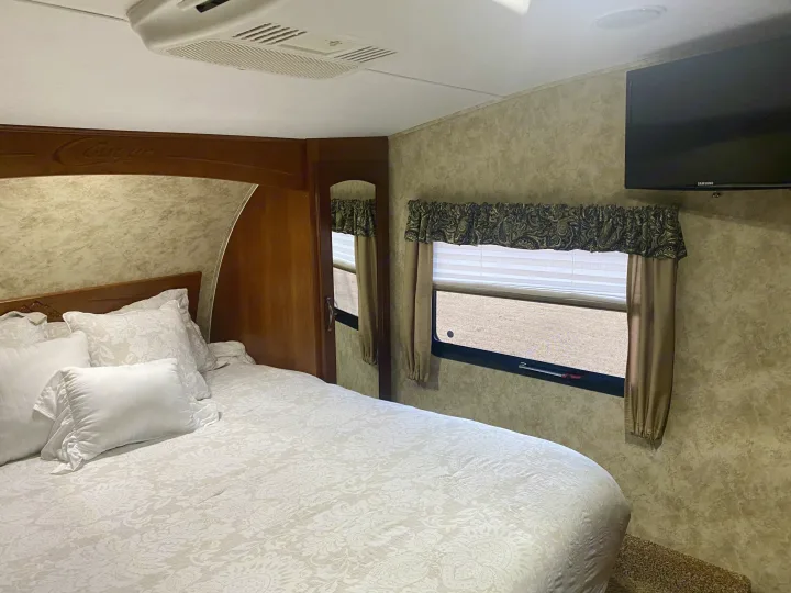 Cozy Cougar RV rental bedroom: features comfy bed, AC, wall TV, and window for a relaxing trip.. Keystone Cougar 2012