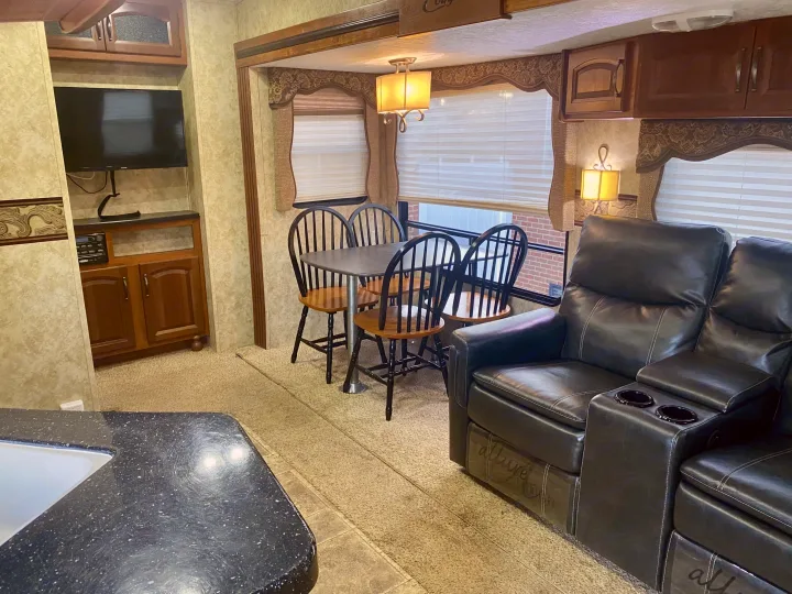 Spacious RV rental living area: black recliners, dining table, TV, and kitchen counter.. Keystone Cougar 2012