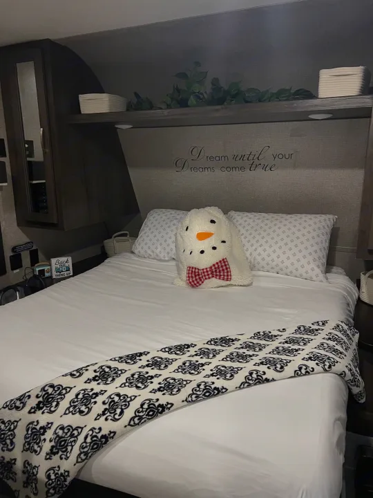 Cozy RV rental bedroom with a snowman pillow, patterned blanket, and "Dream" wall decor.. Jayco Jay Flight SLX 2021