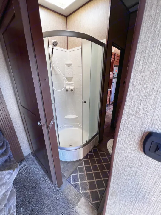 An RV rental's compact bathroom, showcasing a well-lit, glass-enclosed corner shower stall.. Keystone RV Sprinter 2018