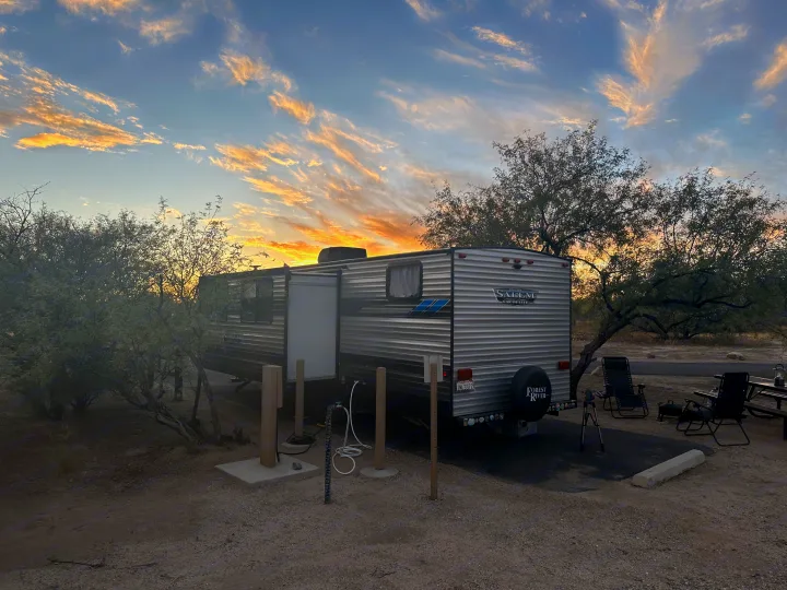 Travel trailer parked at a desert campsite during sunset. A serene view, perfect for your next RV rental adventure.. Forest River Salem Cruise Lite 2022