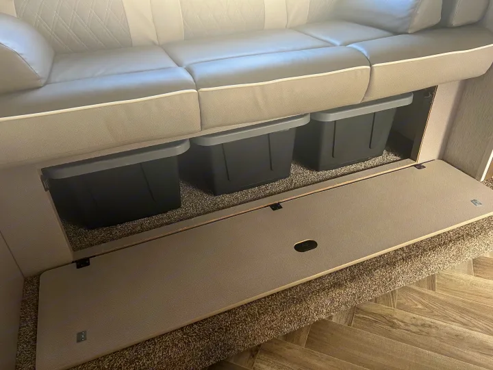 RV rental: Light-colored bench seat with open under-seat access revealing three dark storage bins on a carpeted floor. Efficient interior storage.. Forest River Salem Cruise Lite 2022