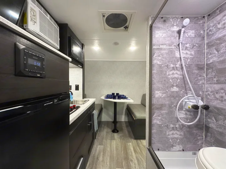 RV rental interior featuring a compact kitchen, dinette with blue dishes, and a functional all-in-one shower bathroom.. Braxton Creek Bushwhacker Plus 2023