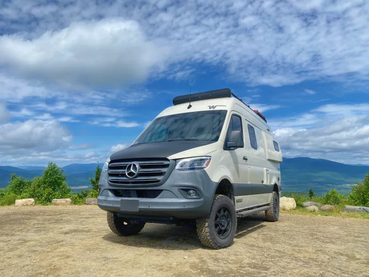 Winnebago Revel Sprinter camper van RV rental parked atop a mountain, offering breathtaking views under a cloudy sky.. Winnebago Revel 2020