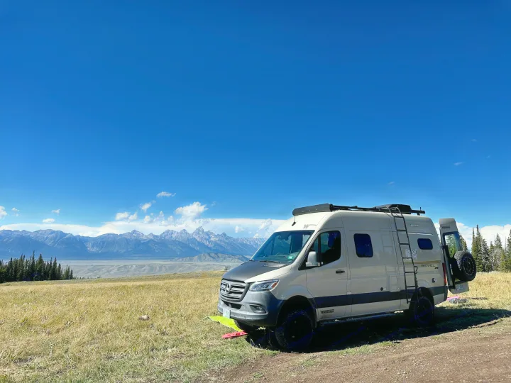 Winnebago Revel rv rental camper van parked in a scenic mountain landscape with grassy fields under a bright blue sky.. Winnebago Revel 2020